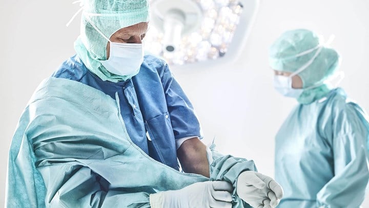 Surgeon donning a gown before surgery